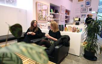 A photograph of two visitors sitting and drinking coffee in the Tate Liverpool + RIBA North cafe