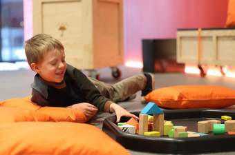 A photograph of a child lying on the floor and playing with building blocks