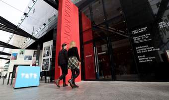 A photograph of two visitors walking into Tate Liverpool + RIBA North