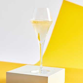 A glass of sparkling wine in front of a geometric background