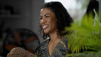 Artist Zohra Opoku smiling with a green plant in the foreground