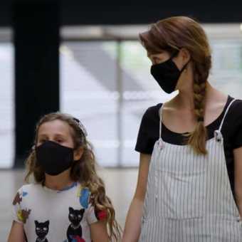 a parent and child wearing face coverings walking into the gallery.