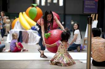 A parent and child playing with a giant fruit prop