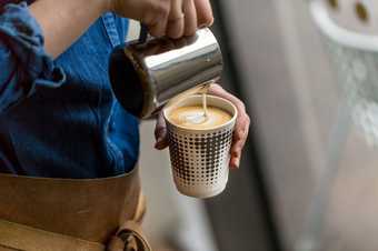 Person pouring milk into a coffee cup