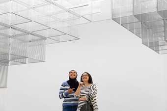 two visitors looking up at installation art