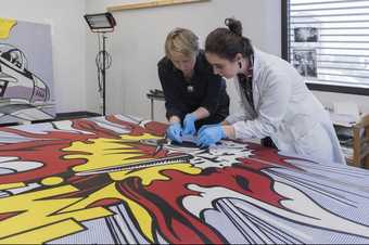 Two conservators working on a painting