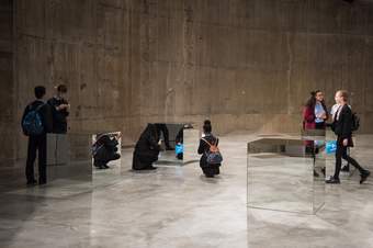 Several students examine four large, mirrored cubes.