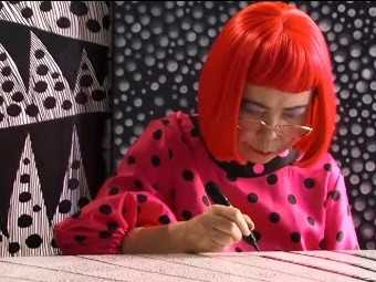 Artist Yayoi Kusama painting on a desk