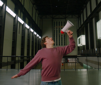 A person speaking into a megaphone with arms open